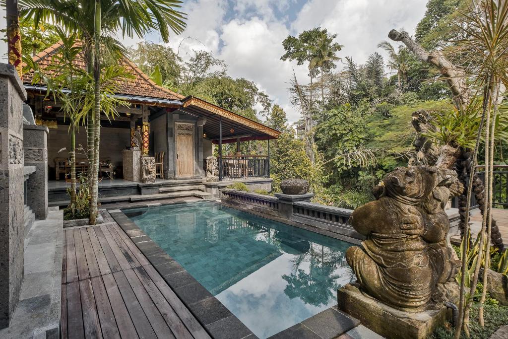乌布Tigata Ubud Cottage的别墅内的游泳池,前面设有雕像