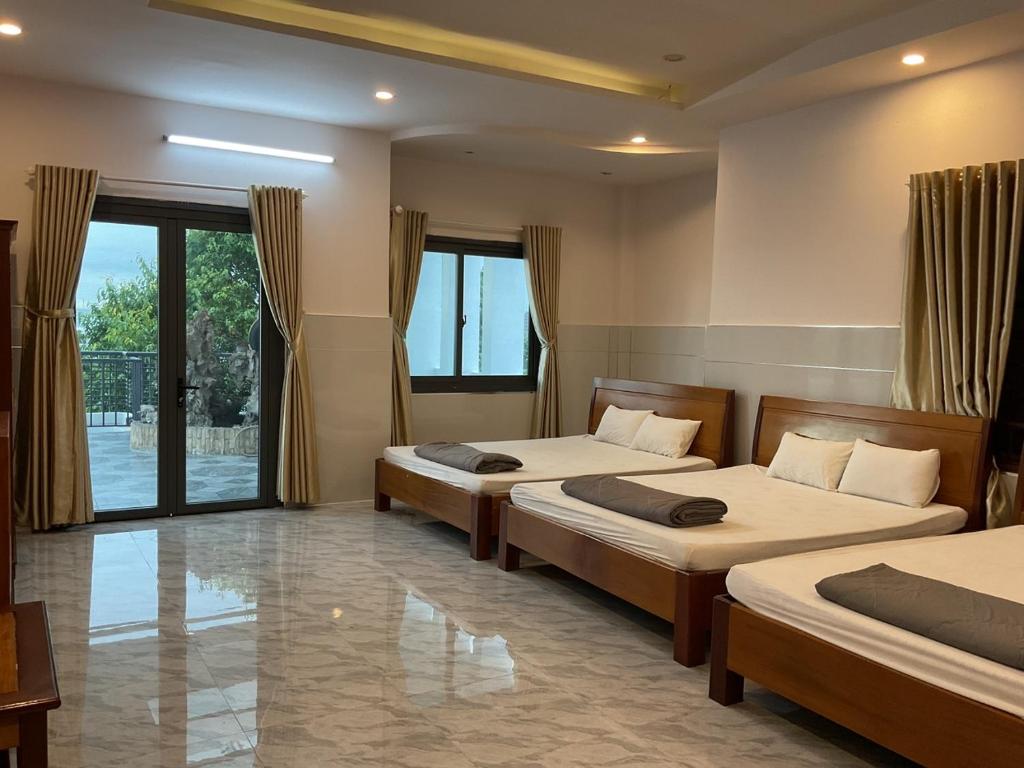 邦美蜀Hoàng Linh Hotel的一间卧室设有两张床和大窗户