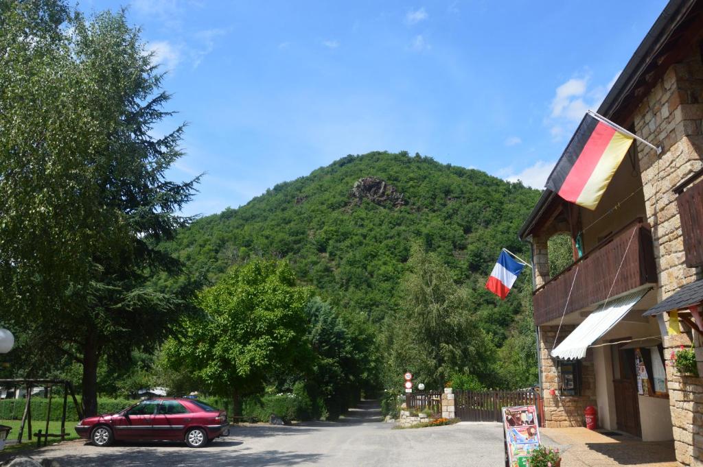 BédouèsCamping Chon du Tarn的停在一座山楼前的红色汽车