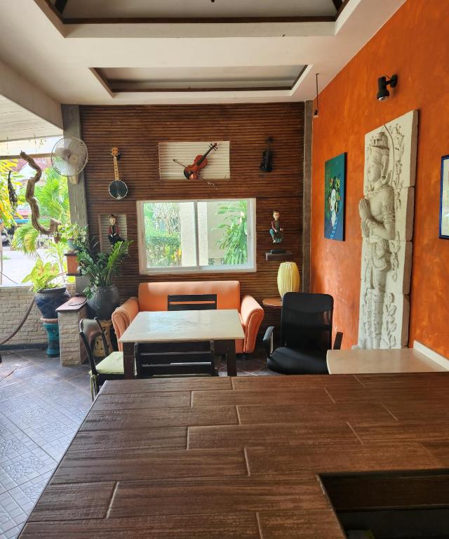 卡马拉海滩Bungalows Musch Kamala Phuket的客厅设有橙色墙壁和桌椅