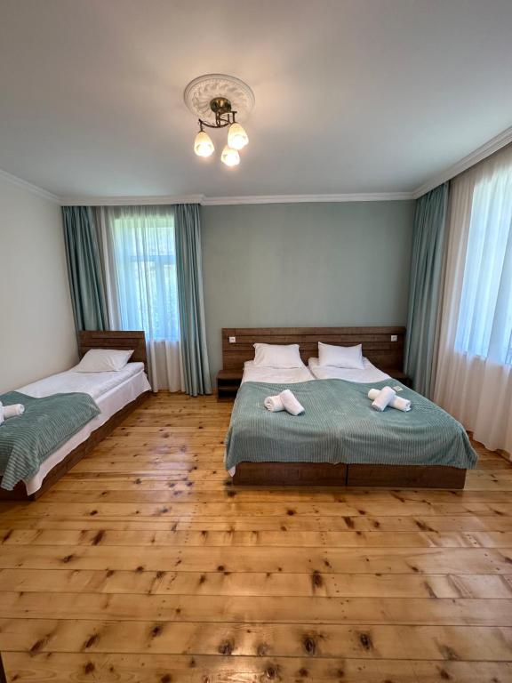 卡兹贝吉Polaris Kazbegi的客房内设有两张床,铺有木地板,设有窗户。