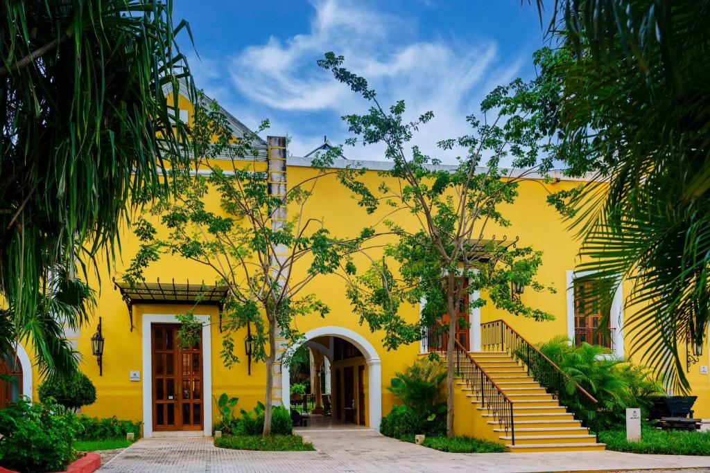 梅里达Hacienda Xcanatun, Angsana Heritage Collection的前面有楼梯的黄色建筑