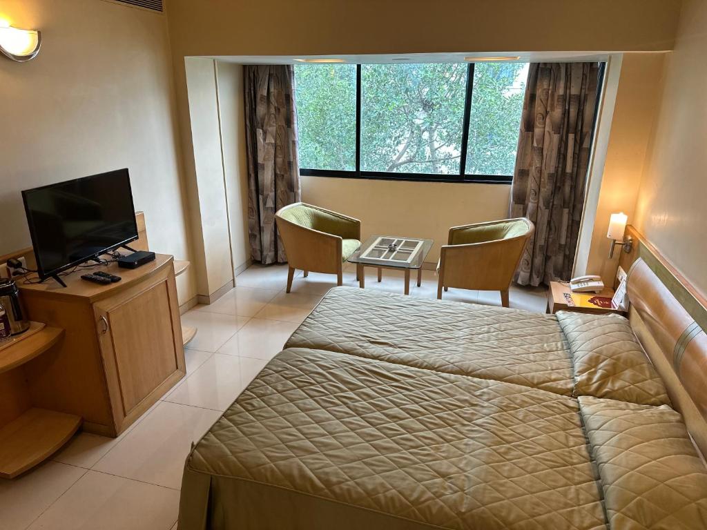 浦那Hotel Ashirwad的酒店客房配有一张床、一张书桌和一台电视。