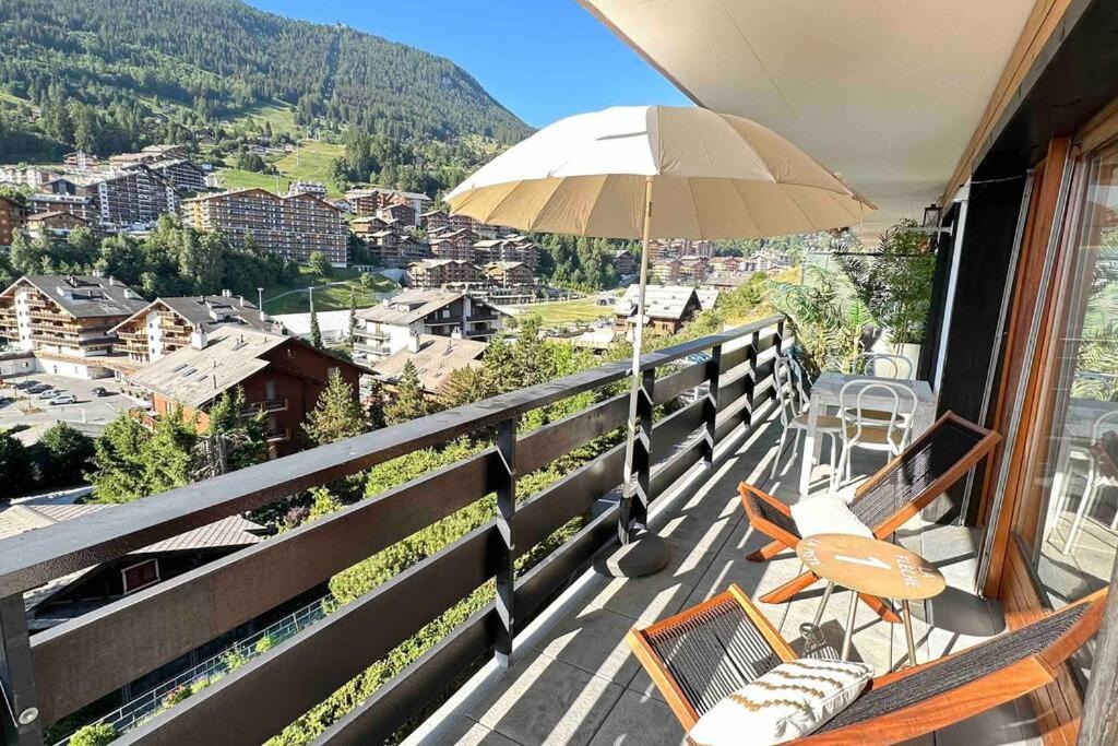 南达Sunny mountain view apartment in town by Jolidi的阳台配有椅子和遮阳伞。