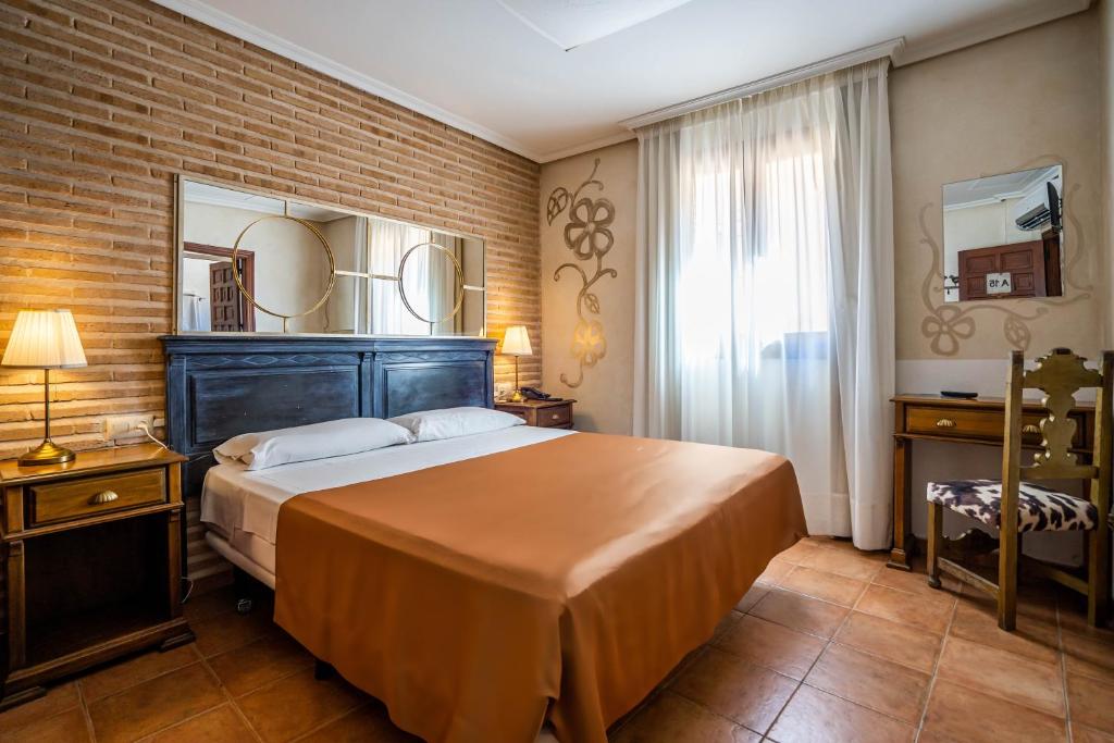 托莱多YIT Puerta Bisagra的一间卧室设有一张大床和砖墙