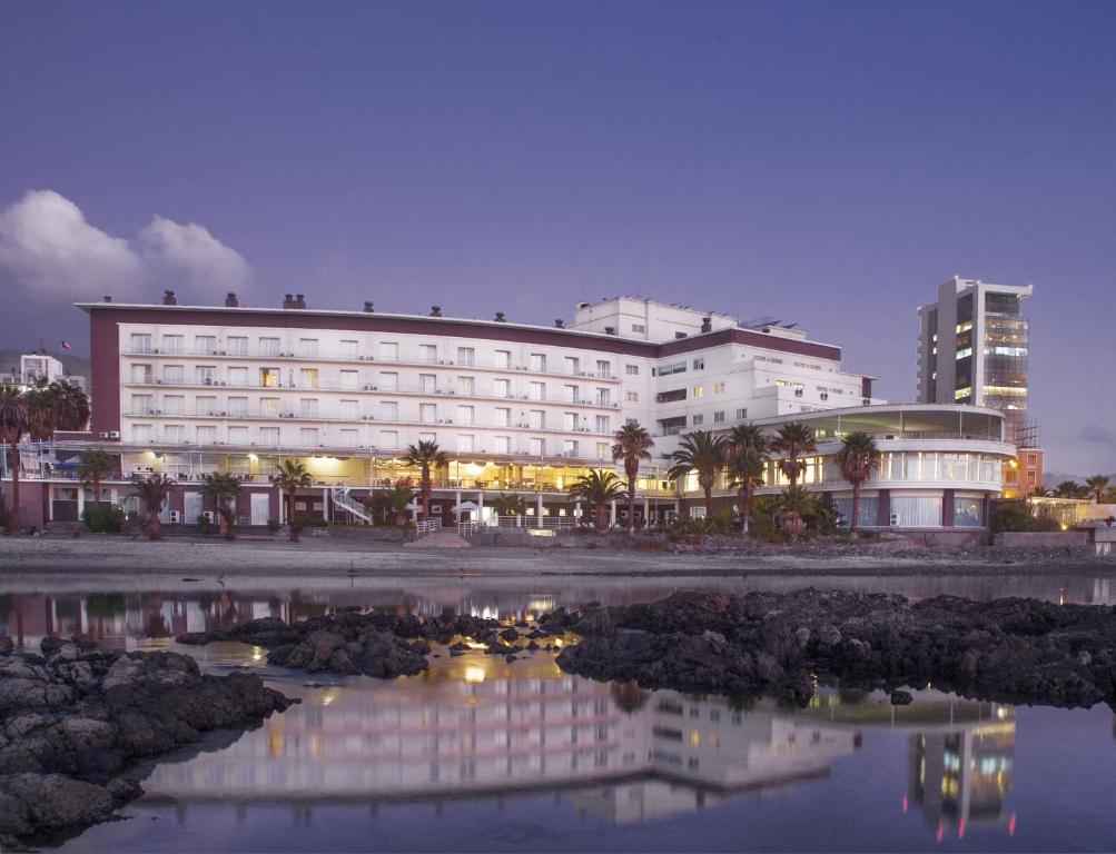 安托法加斯塔Hotel Antofagasta的一座白色的大建筑,在水体中反射