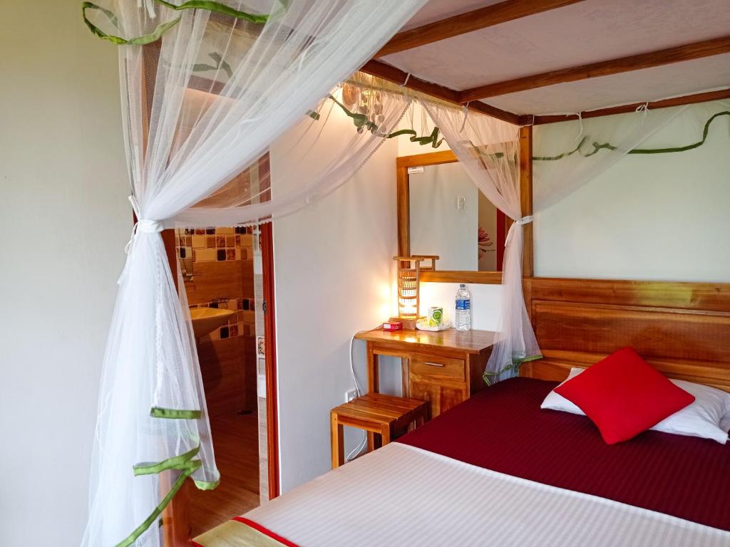 代尼耶耶Rainforest Nest的一间卧室配有一张红色和白色天蓬床