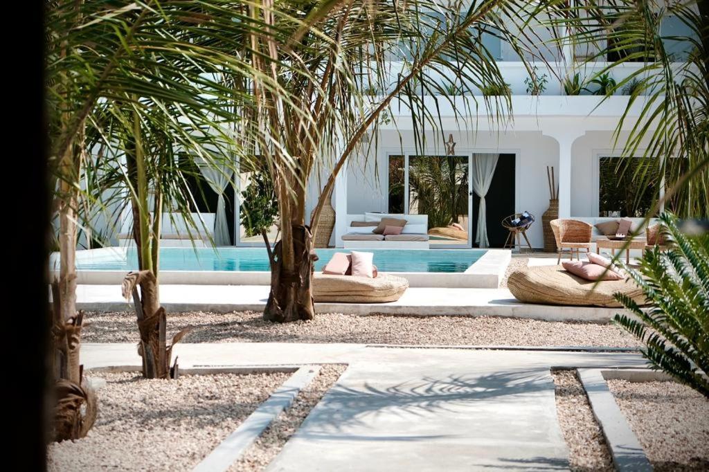 吉汶瓦Antares Villa的一间种植了棕榈树和游泳池的客厅