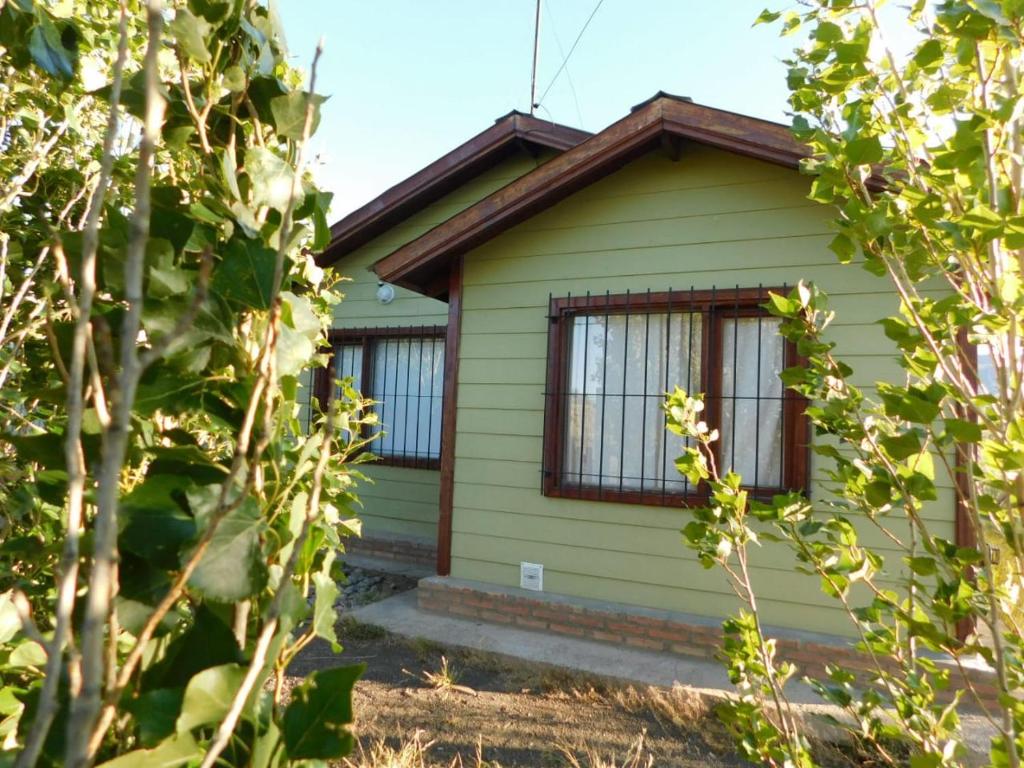 埃尔卡拉法特CABAÑAS LOS COIRONES的黄色的房子,有窗户和一些树木
