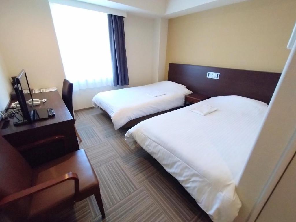 白山市New Matto Terminal Hotel - Vacation STAY 01878v的酒店客房设有两张床、一张书桌和一个窗户。