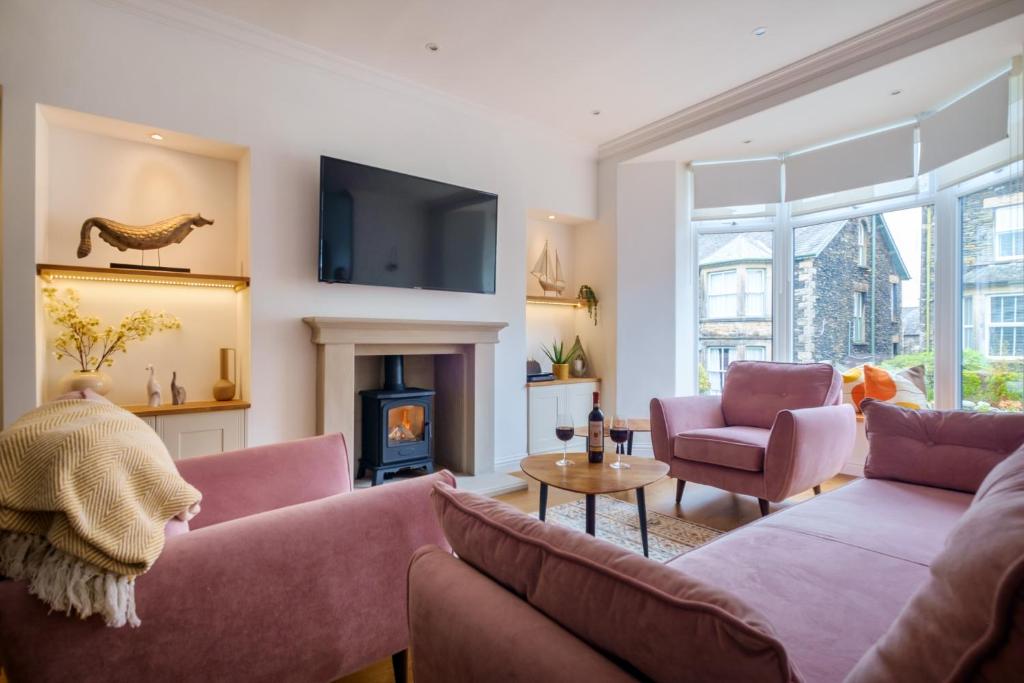 鲍内斯温德米尔Canon Craig, Luxurious Lakeland stone Cottage的客厅配有2张粉红色的沙发和壁炉