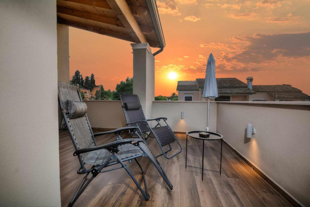 AlepouStratos house!的阳台上配有两把椅子和一张桌子,享有日落美景