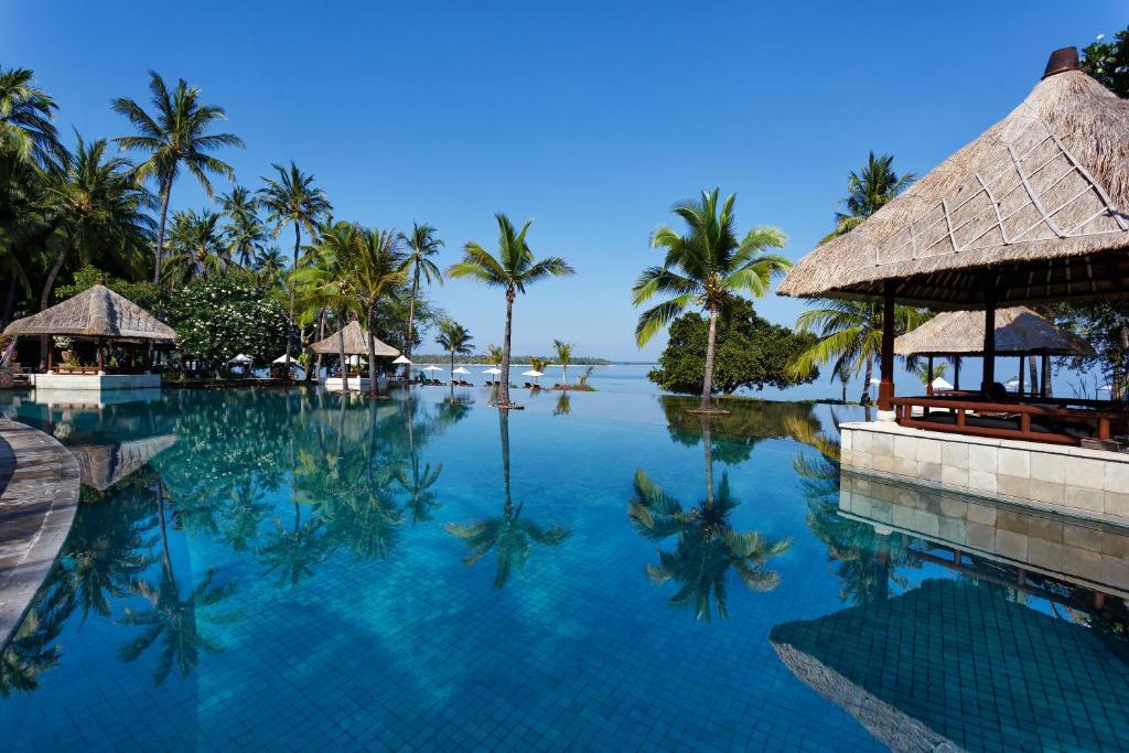 丹戎The Oberoi Beach Resort, Lombok的棕榈树度假村的游泳池