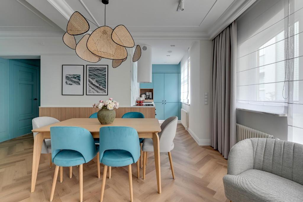 索波特Lion Apartments - Havana Premium Family Stay的一间带木桌和蓝色椅子的用餐室