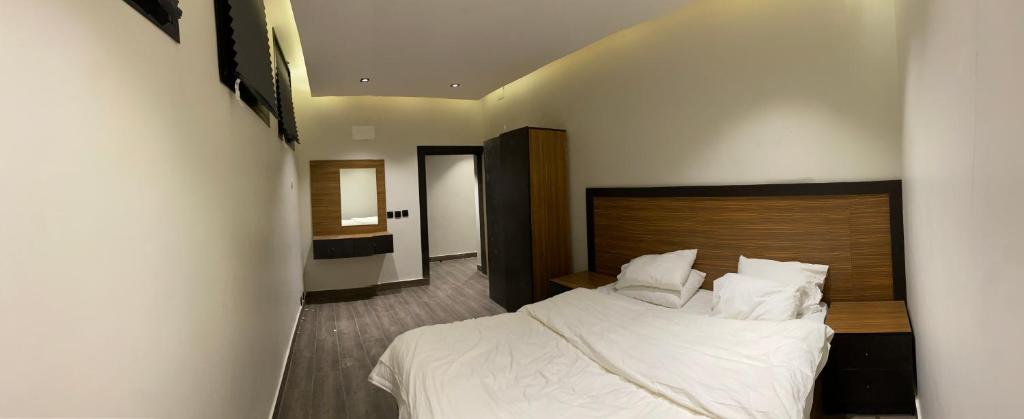 阿哈达Al Hada的卧室配有白色的床和木制床头板