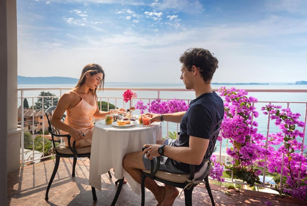 加尔多内-里维耶拉佛罗里达别墅酒店套房&套房公寓的坐在阳台上桌子上的男人和女人