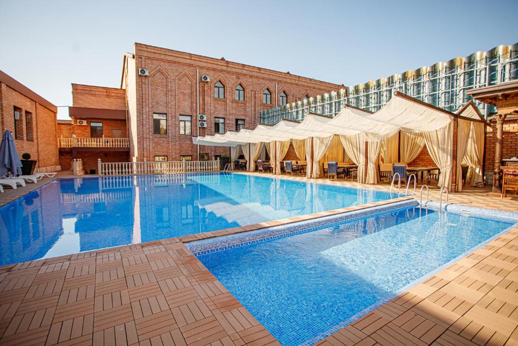 塔什干Ichan Qal'a Premium Class Hotel的一座大型游泳池,位于一座带帐篷的建筑旁边