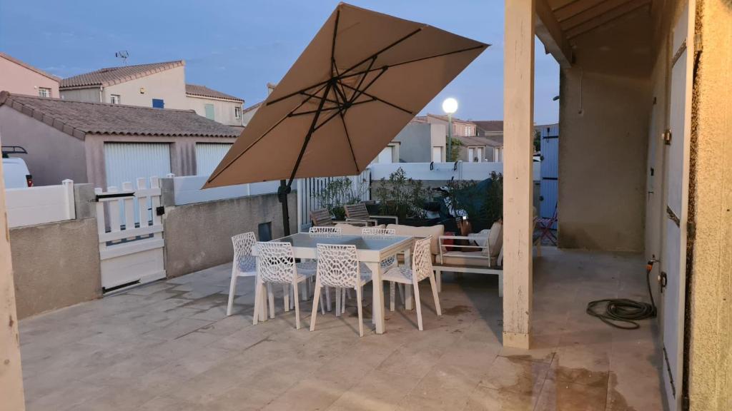 波尔蒂拉盖Villa 6 personnes dans résidence avec piscine的庭院配有桌椅和遮阳伞。