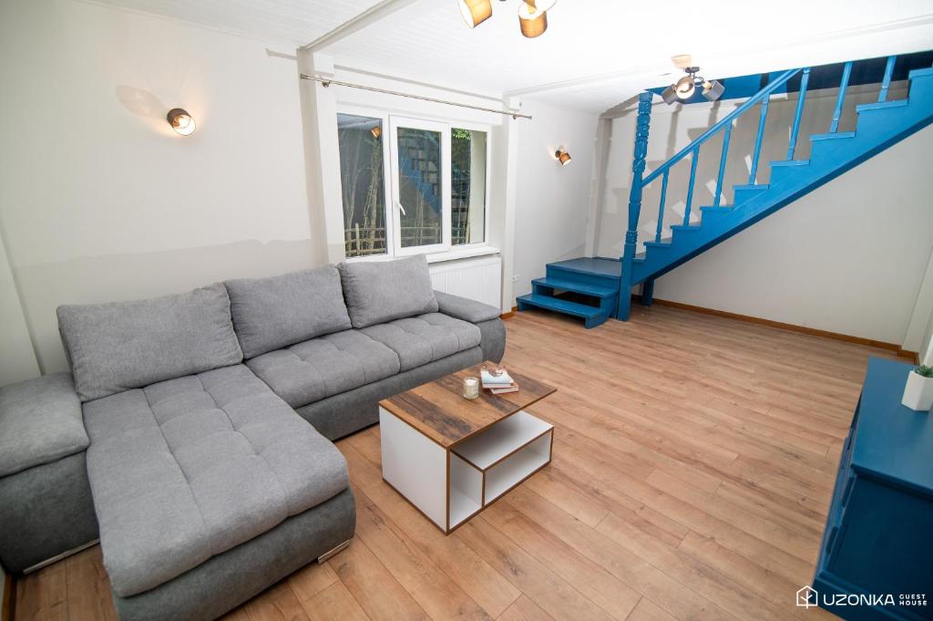 Ozunca-BăiUzonka Guesthouse的带沙发和蓝色楼梯的客厅