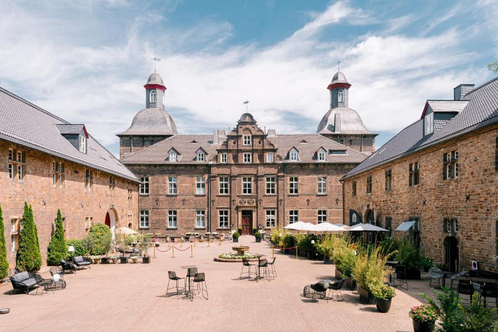 埃森胡根普特城堡酒店的一座带桌椅的大型砖砌建筑的庭院