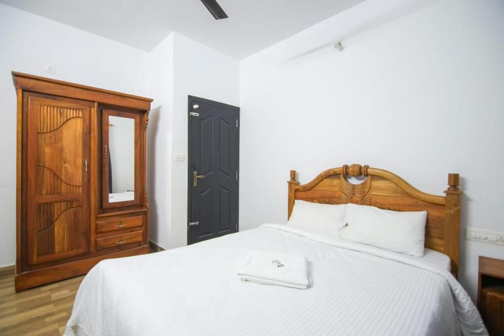瓦亚纳德B'camp Resorts & Homestays的一间卧室配有一张带木制床头板和门的床。