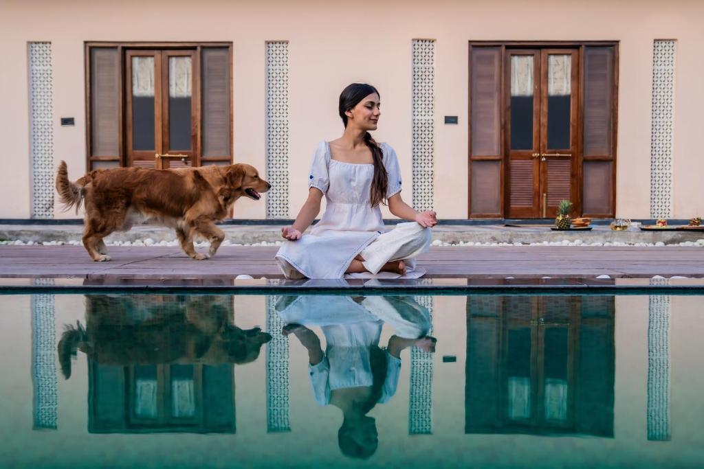 乌代浦Parijat Private Pool Villa 1, 2 and 3 BHK的和狗一起坐在游泳池旁的女人