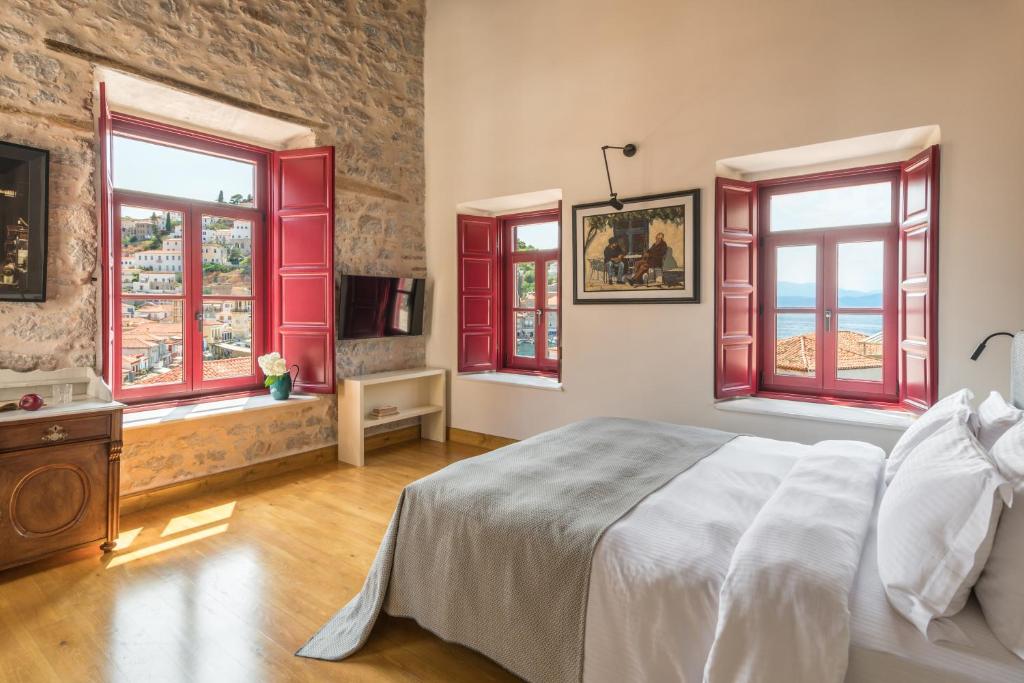 伊兹拉FOS Hydra residence的卧室设有红色窗户和一张大床