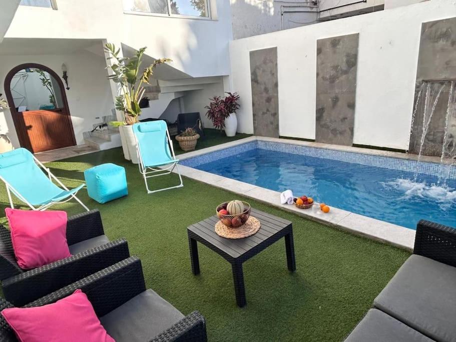 拉马萨Villa du Bey à La Marsa的客厅设有游泳池、椅子和桌子