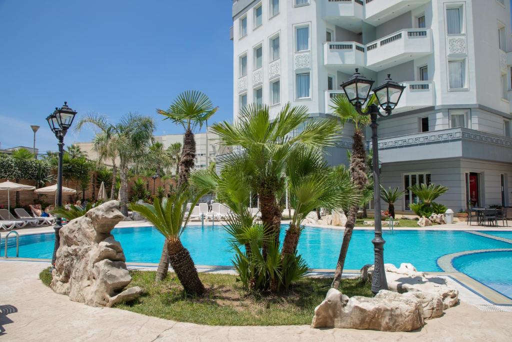 都拉斯迪拉酒店的一座带游泳池、棕榈树和大楼的度假村