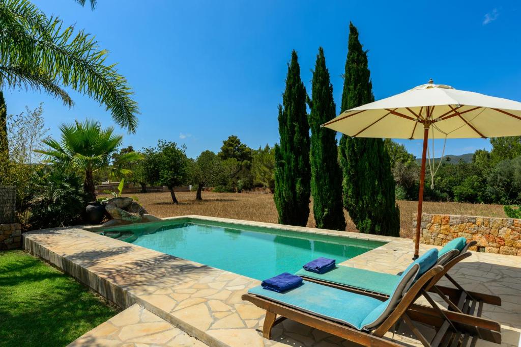 圣卡洛斯Villa Can Curreu的一个带遮阳伞和椅子的游泳池
