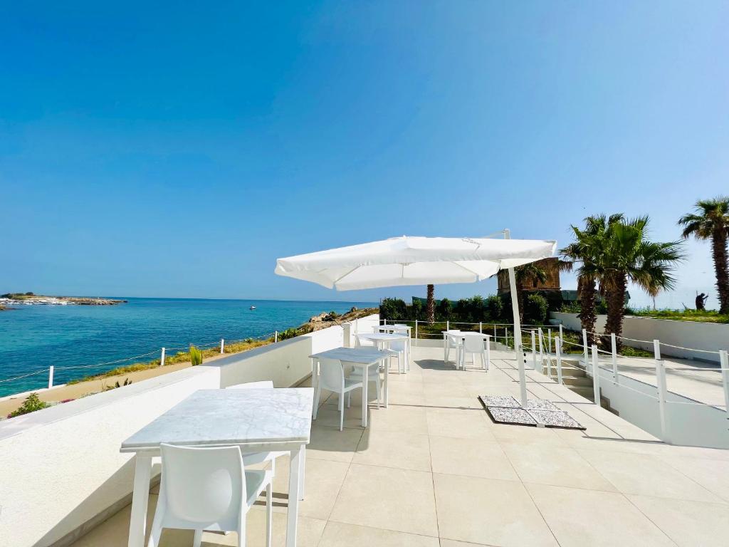 奇尼斯Torre Pozzillo Beach的一个带桌子和遮阳伞的庭院,俯瞰着大海