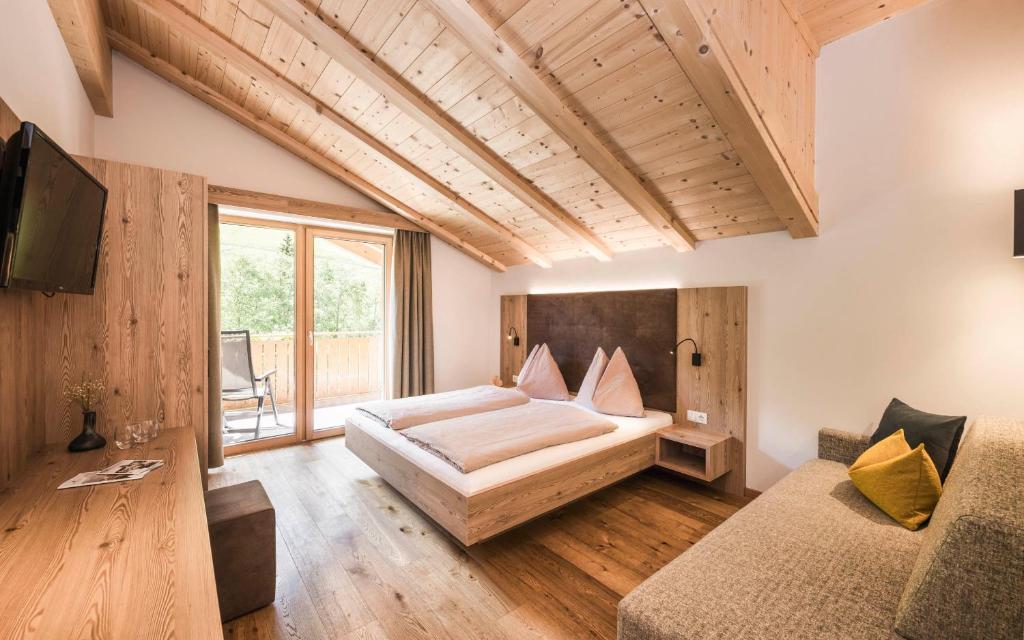 拉辛Gasthof Jaufensteg的一间卧室配有一张大床和一张沙发
