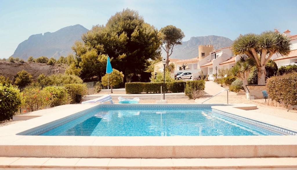 拉尔法斯德尔皮VIP Alfaz del Pi的一座游泳池,位于一个种有树木和房屋的庭院内
