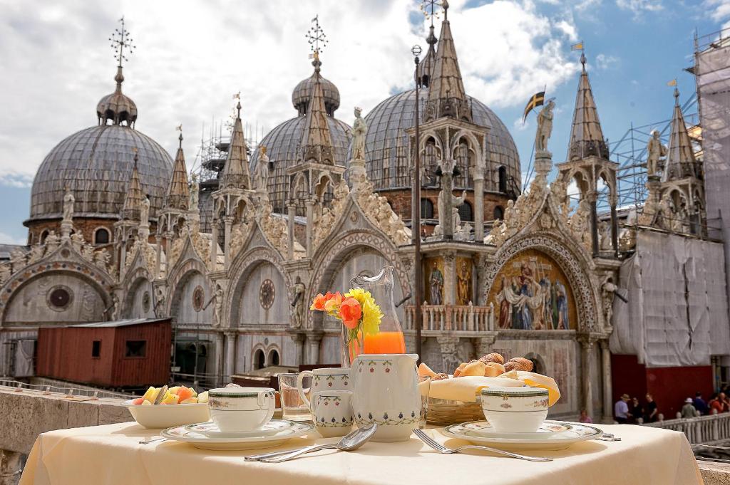 威尼斯Canaletto Luxury Suites - San Marco Luxury的教堂前带食物盘的桌子