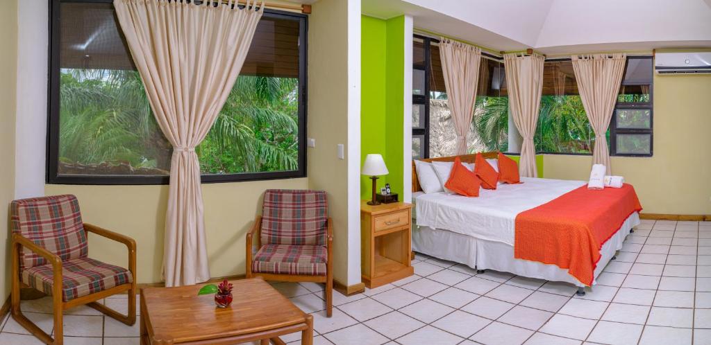 里约杜尔塞Banana Palms Hotel的一间卧室配有一张床、两把椅子和一张桌子