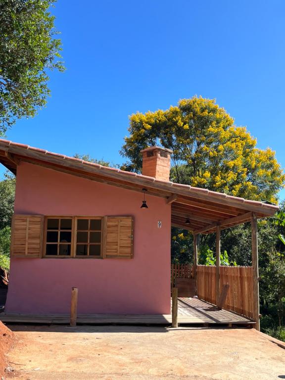 库尼亚Pousada Recanto dos Pássaros的一座小粉红色的房子,有树