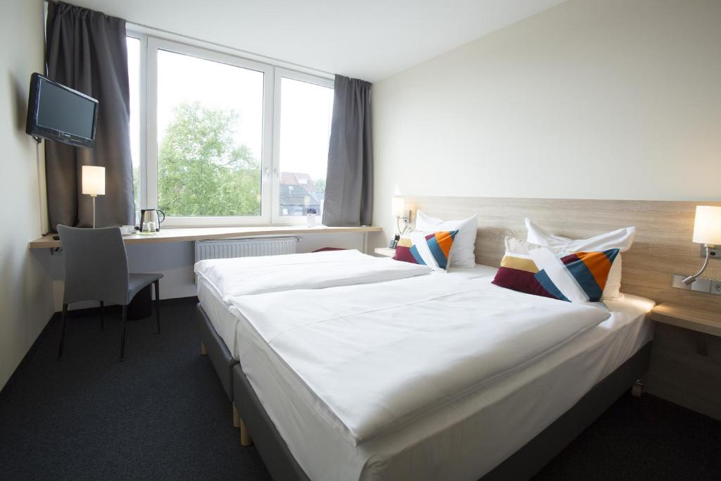 不来梅港弗洛登齐尔大西洋酒店的酒店客房设有一张白色大床和一个窗户。