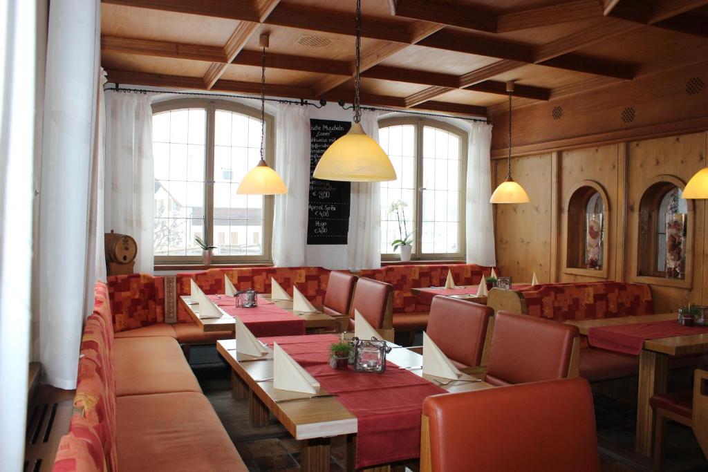 罗斯豪普滕陶尔米纳比萨餐厅旅馆的餐厅设有红色的桌椅和窗户。
