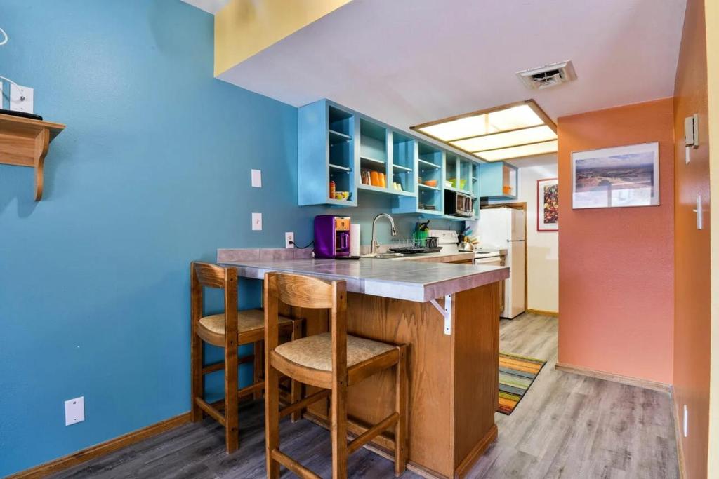 摩押Near Downtown Adventure Nest - Rose Tree 4的厨房设有蓝色的墙壁和带凳子的台面。