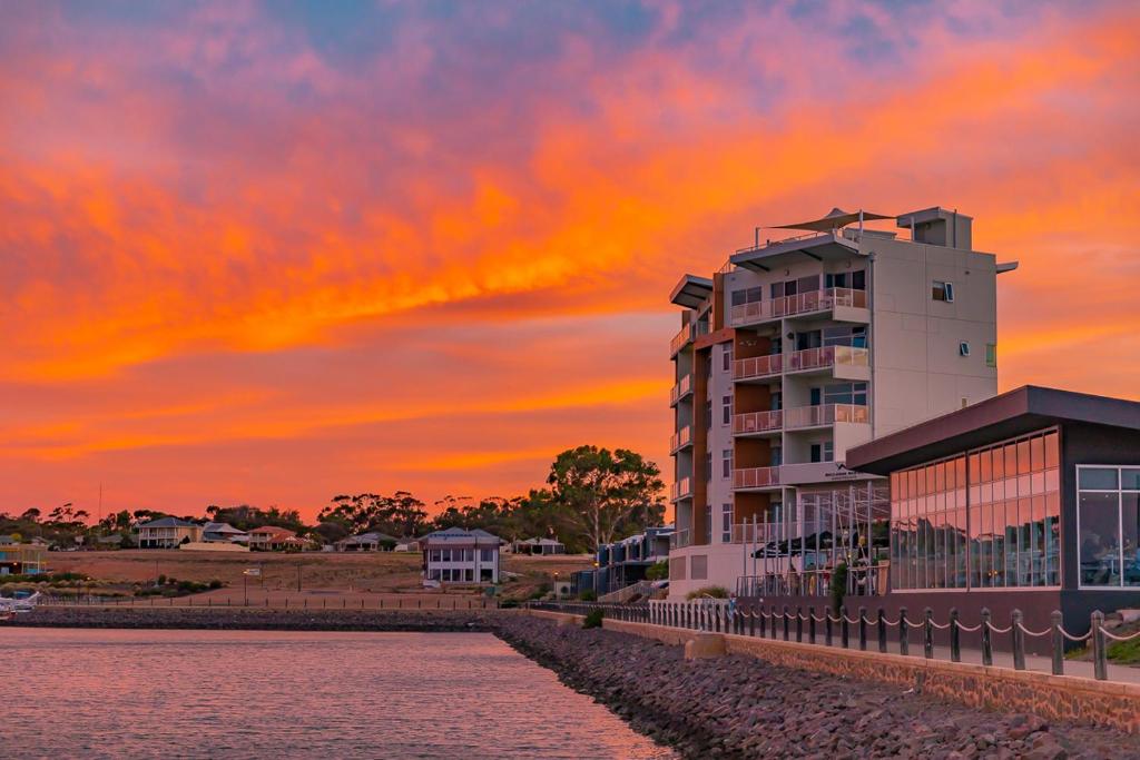 沃拉鲁袋鼠滨海公寓酒店的靠近水体的建筑物,日落