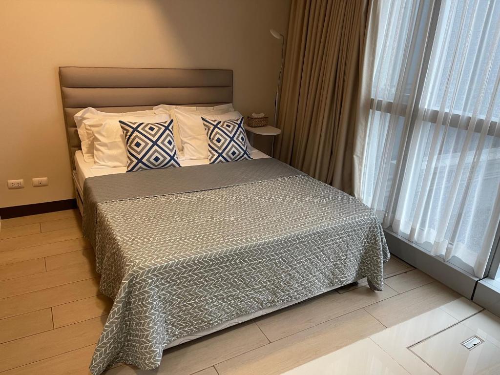 马尼拉1 BR condo Uptown Parksuites BGC, high floor, morning sun的卧室配有带枕头的床铺和窗户。