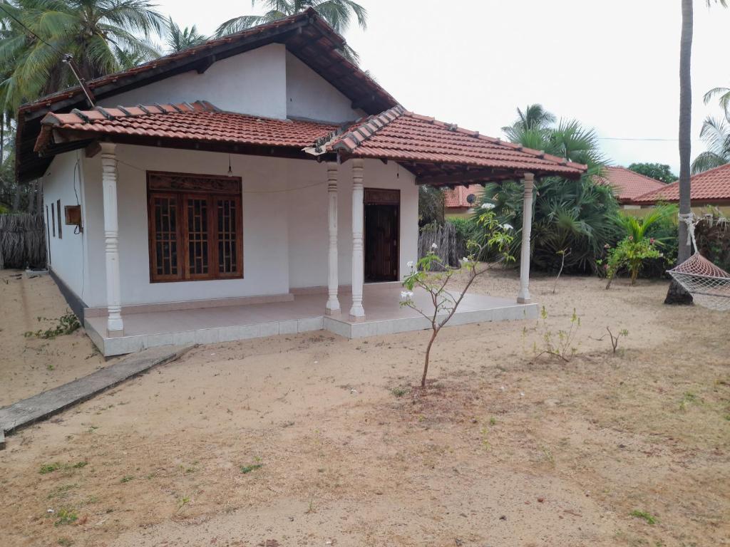 卡尔皮蒂耶Rosa Kusum Vacation Home Near Kudawa Beach In Kalpitiya的一间白色的小房子,有红色的屋顶