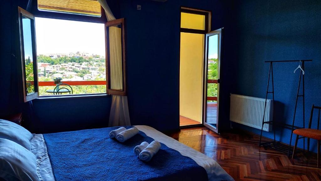 西格纳吉Guesthouse ''Door'' in Sighnaghi的一间卧室设有蓝色的墙壁和一张带两条毛巾的床。