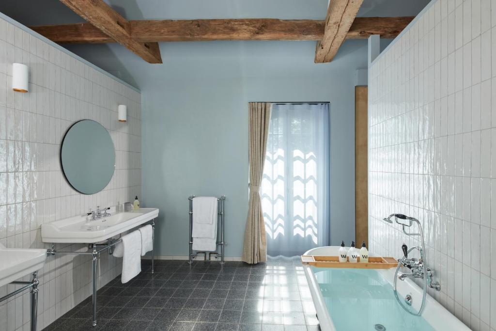 PloerenDOMAINE LE MEZO的带浴缸、水槽和镜子的浴室