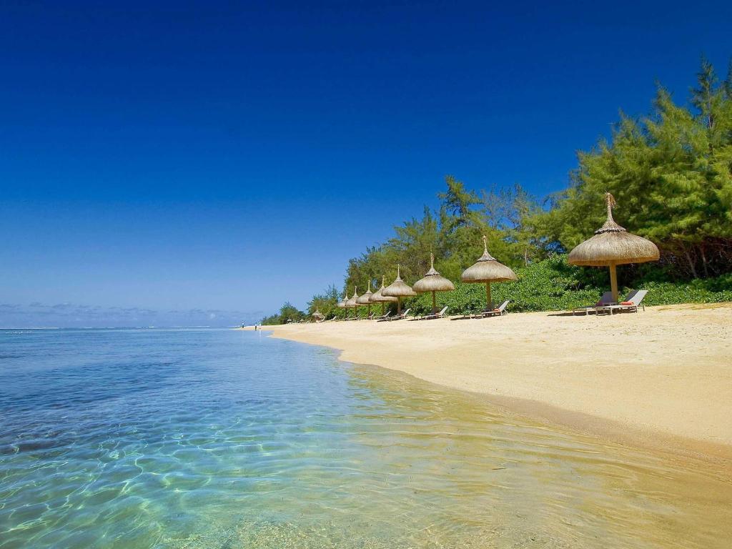 贝隆布尔SO/ Sofitel Mauritius的一片带一些草伞和水的海滩