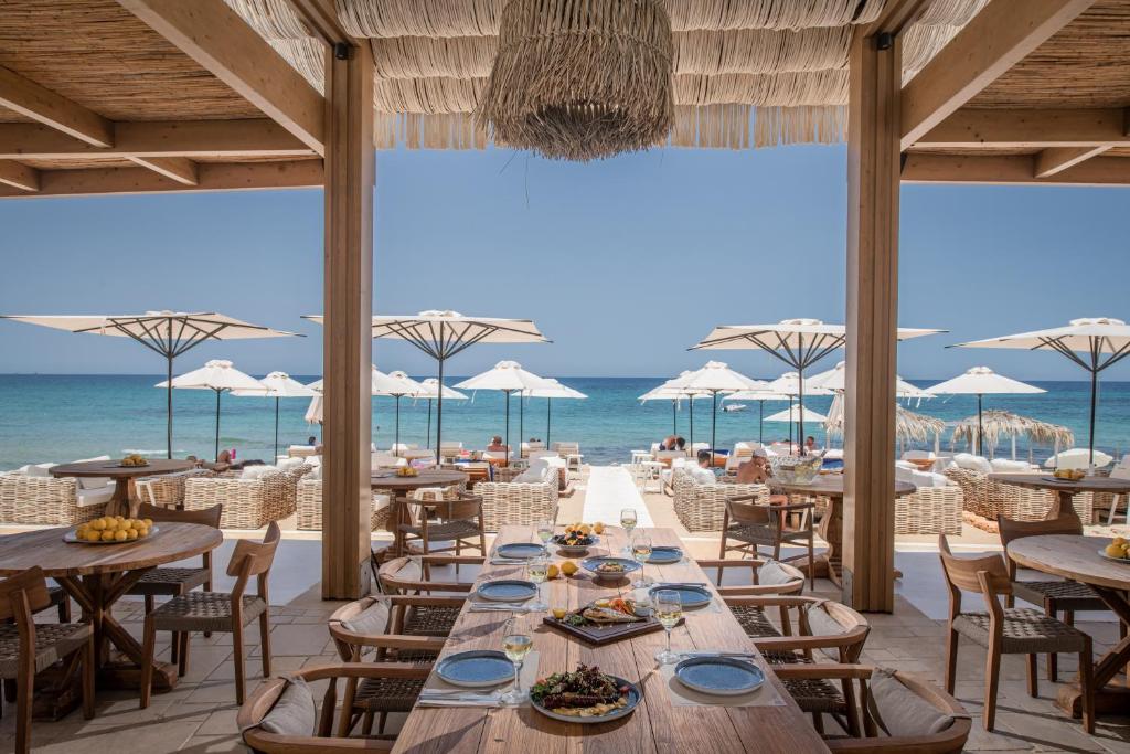 玛利亚帕特尼斯海滩海滨套房酒店的海滩上的餐厅,配有桌椅
