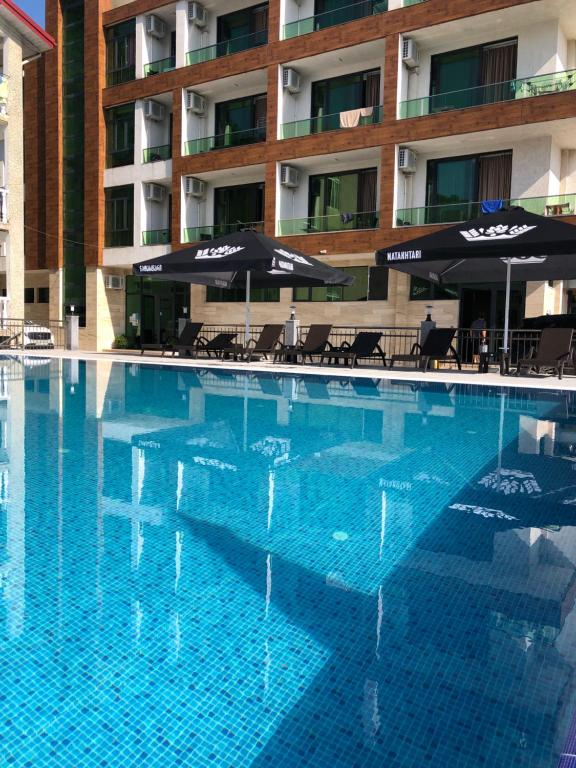 乌雷基Magnetiti Hotel的一个带遮阳伞的大型游泳池和酒店