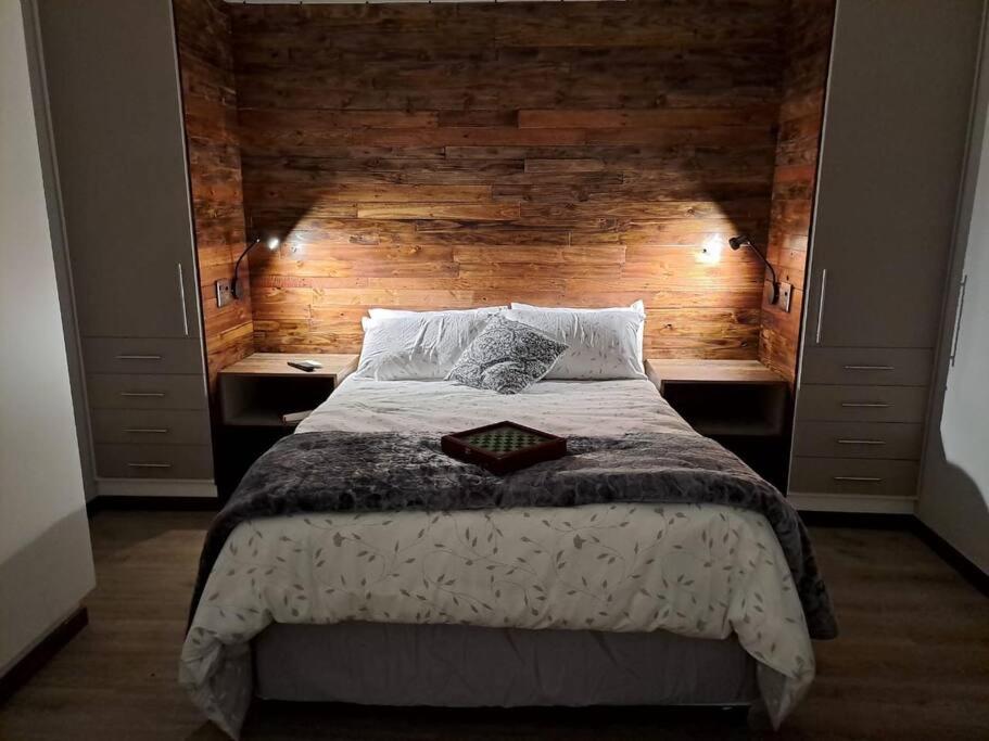 布隆方丹Mossie Nes - Self Catering的一间卧室设有一张带木墙的大床