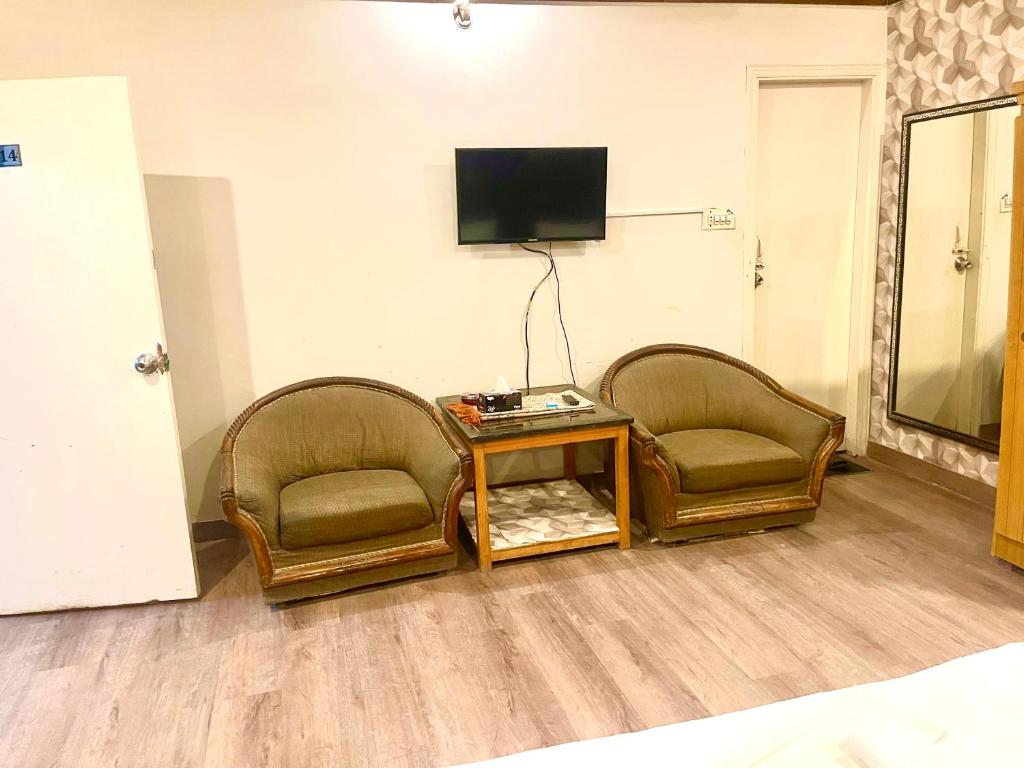 卡拉奇Rehaish Inn的配有电视的客房内的2把椅子和1张桌子