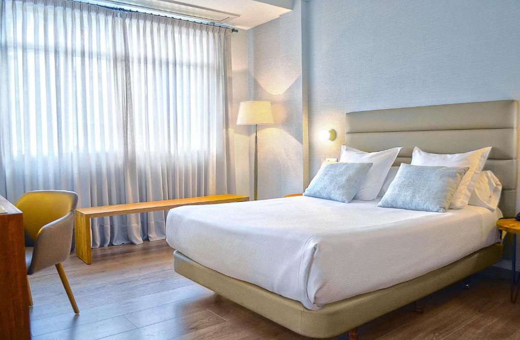 庞特维德拉巴哈斯海岸酒店的配有一张床、一张书桌和一扇窗户的酒店客房